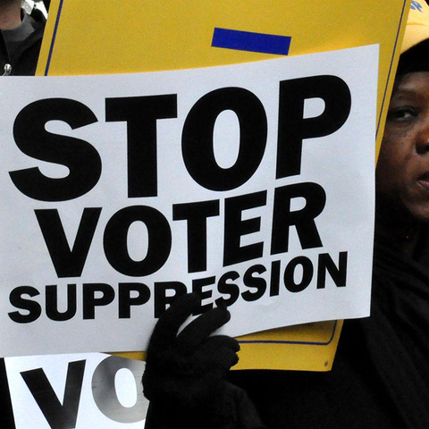 Person holding sign that reads "Stop Voter Suppression"